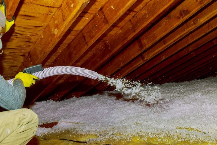 Man installing blow-in insulation in the attic.