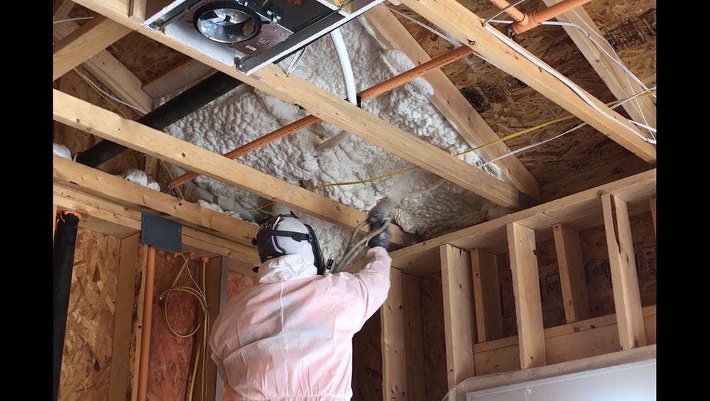 Man spraying attic insulation using spray foam in the attic.