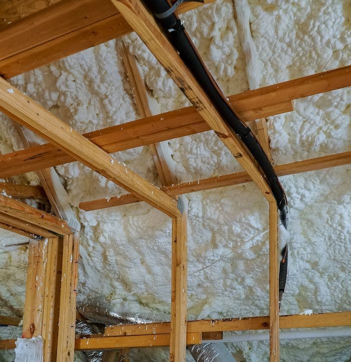Spray foam in attic around wooden beams.